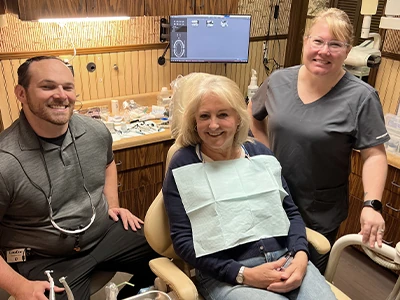 Dr. Albergotti and staff smiling with a patient during a dental exam